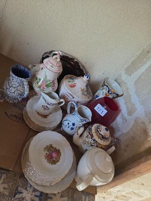une boîte remplie de tasses à thé et de soucoupes posée par terre