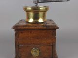 un moulin à café ancien avec un socle en bois et une plaque en laiton