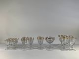 six wine glasses with gold rims are lined up on a table