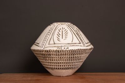 a white vase sitting on top of a wooden table