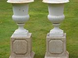 two white vases sitting on top of each other in the grass