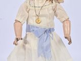 a doll that is wearing a white dress and a hat