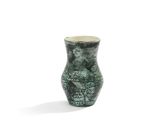 un vase vert posé sur une surface blanche