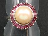 bague avec perle rose et blanche posée sur un socle en acrylique transparent