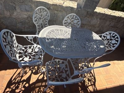 une table et des chaises blanches installées dehors, sur une terrasse