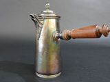 a silver coffee pot with a wooden handle on a table
