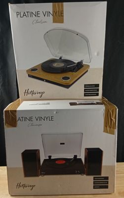 two boxes of a record player sitting on top of a wooden table