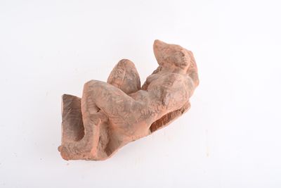 une sculpture en argile représentant une personne allongée sur une surface blanche