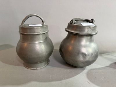two silver pots sitting next to each other on a table