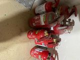 several fire extinguisors are lined up on the floor next to a wall