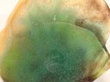 a green and yellow piece of rock on a white surface