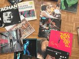 a lot of music books on the floor next to a pair of sneakers