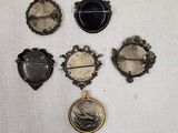 six broches anciennes de formes et de tailles variées, disposées sur un tissu blanc