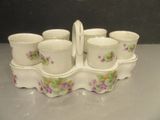 six cups and a tray with a handle on a table