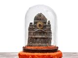 une horloge miniature placée sous un dôme en verre, posée sur une table