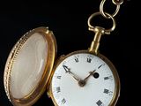 a gold pocket watch with roman numerals on it