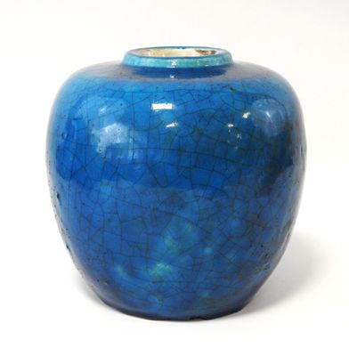 un vase bleu posé sur une surface blanche