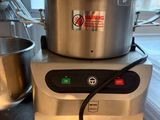 une grande casserole posée sur un plan de travail, à côté d'un robot ménager