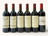 six bottles of wine are lined up in a row on a white surface
