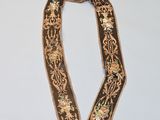 a close up of a brown and gold neck piece on a white surface