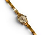 une image d'une montre-bracelet en or sur une surface blanche