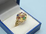 une photo d'une bague en or sertie de pierres multicolores, présentée dans un écrin bleu