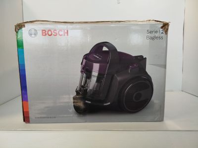 une boîte contenant un aspirateur posée sur une étagère devant un mur blanc