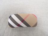 a brown and pink plaid pill case sitting on the ground