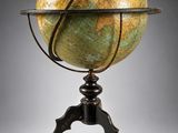 un vieux globe terrestre posé sur un trépied muni d'un socle métallique