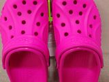 a pair of pink children ' s crocs with green handles