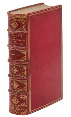 un vieux livre avec une couverture rouge et des bordures dorées sur fond blanc