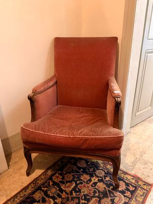 une chaise rouge placée dans une pièce où il y a un tapis au sol