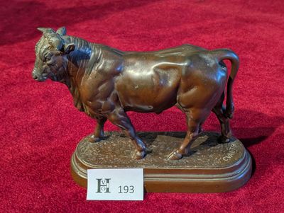 une statue en bronze représentant un taureau, exposée sur un tapis rouge