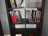 une bibliothèque noire remplie de DVD dans une pièce