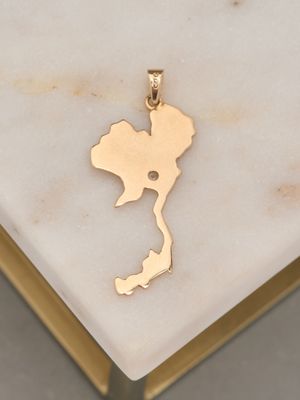 a close up of a gold pendant on a marble surface
