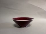a red and white bowl sitting on a white surface