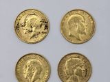 four gold sovereigns are shown on a white surface