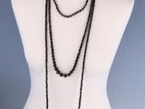 un torse de mannequin sur lequel est posé un collier de perles noires