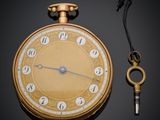 a gold pocket watch with a key attached to it