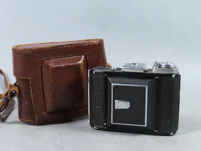 un petit appareil photo et un portefeuille posés sur la table