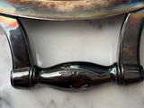 a silver plate with a handle on a marble table