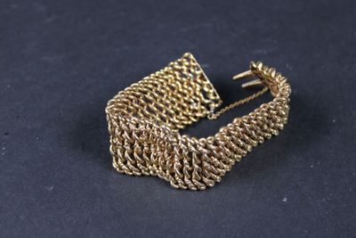 gros plan d'un bracelet en or sur une surface noire