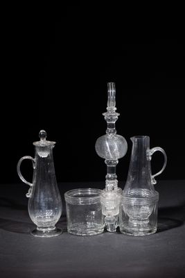 three clear glass vases and a candle holder sitting on a table