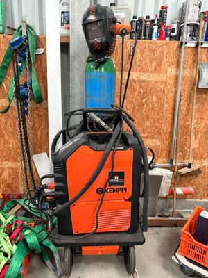une soudeuse orange et noire posée dans un garage, à côté d'un tas d'outils