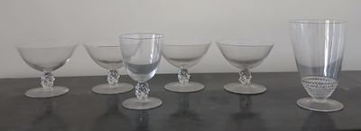cinq verres à vin posés sur une table, avec un mur blanc en arrière-plan