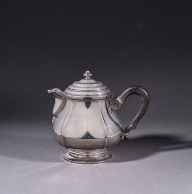 a silver tea pot with a handle on a table