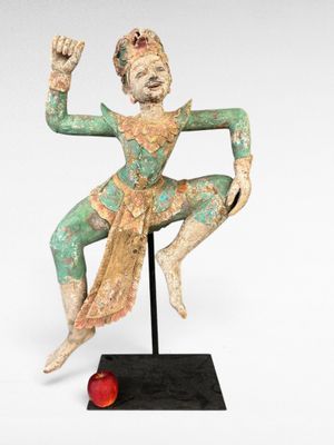 une image représentant la statue d'un homme tenant une pomme rouge