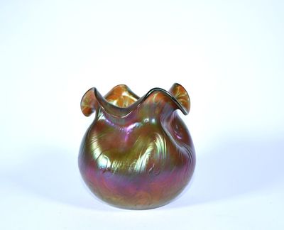 un vase en verre coloré muni d'une anse incurvée, posé sur une surface blanche