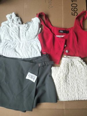 trois vêtements disposés sur une boîte en carton, avec une étiquette de prix