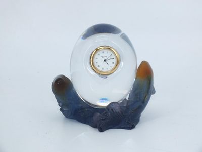 a small clock sitting on top of a blue and white figurine